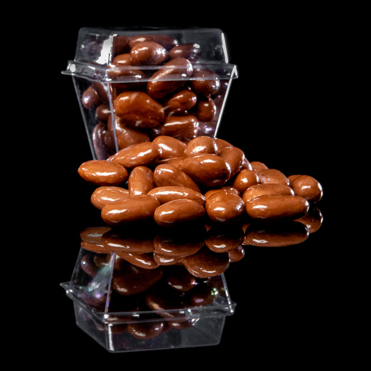 Milk chocolate-covered almonds in a 2.5 oz clear plastic hinged container, with several individual almonds displayed in front against a black background