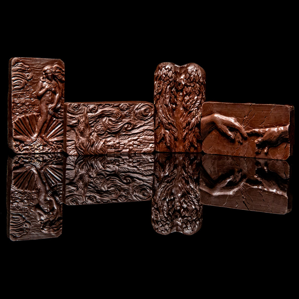 Set of four dark chocolate art bars featuring embossed designs of The Birth of Venus, Starry Night, Angel Wings, and The Creation of Adam displayed against a black background