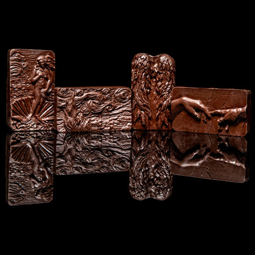 Set of four dark chocolate art bars featuring embossed designs of The Birth of Venus, Starry Night, Angel Wings, and The Creation of Adam displayed against a black background
