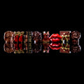 A row of novelty chocolate candies shaped like male muscular bodies, red bottles, a sign reading 'SEX WORK', red lips, and a gift box, arranged on a reflective black surface against a black background.